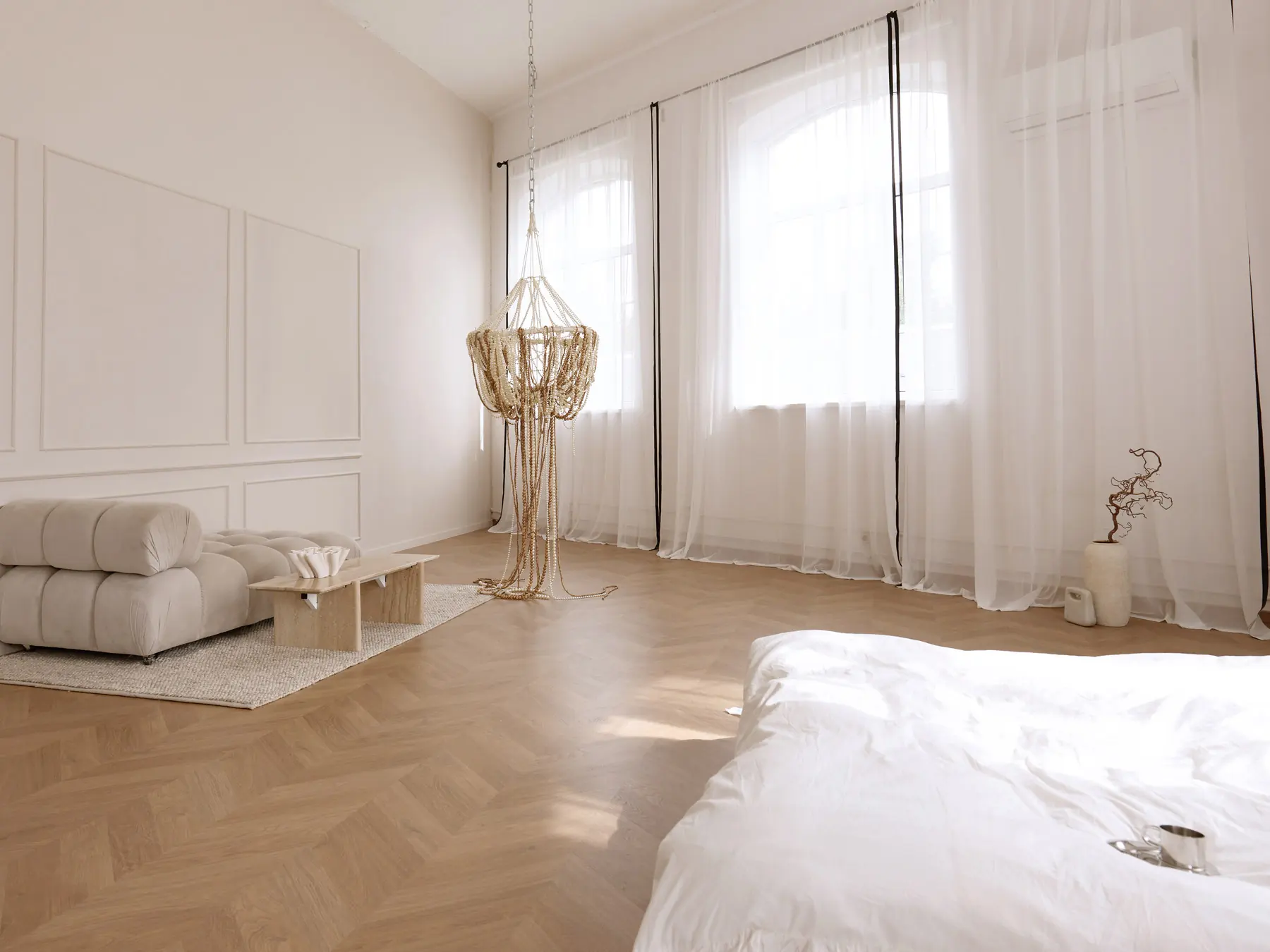 Home Chic zāle kopskatā: augsti arku logi, moduļu dīvāns un pērļu lustra