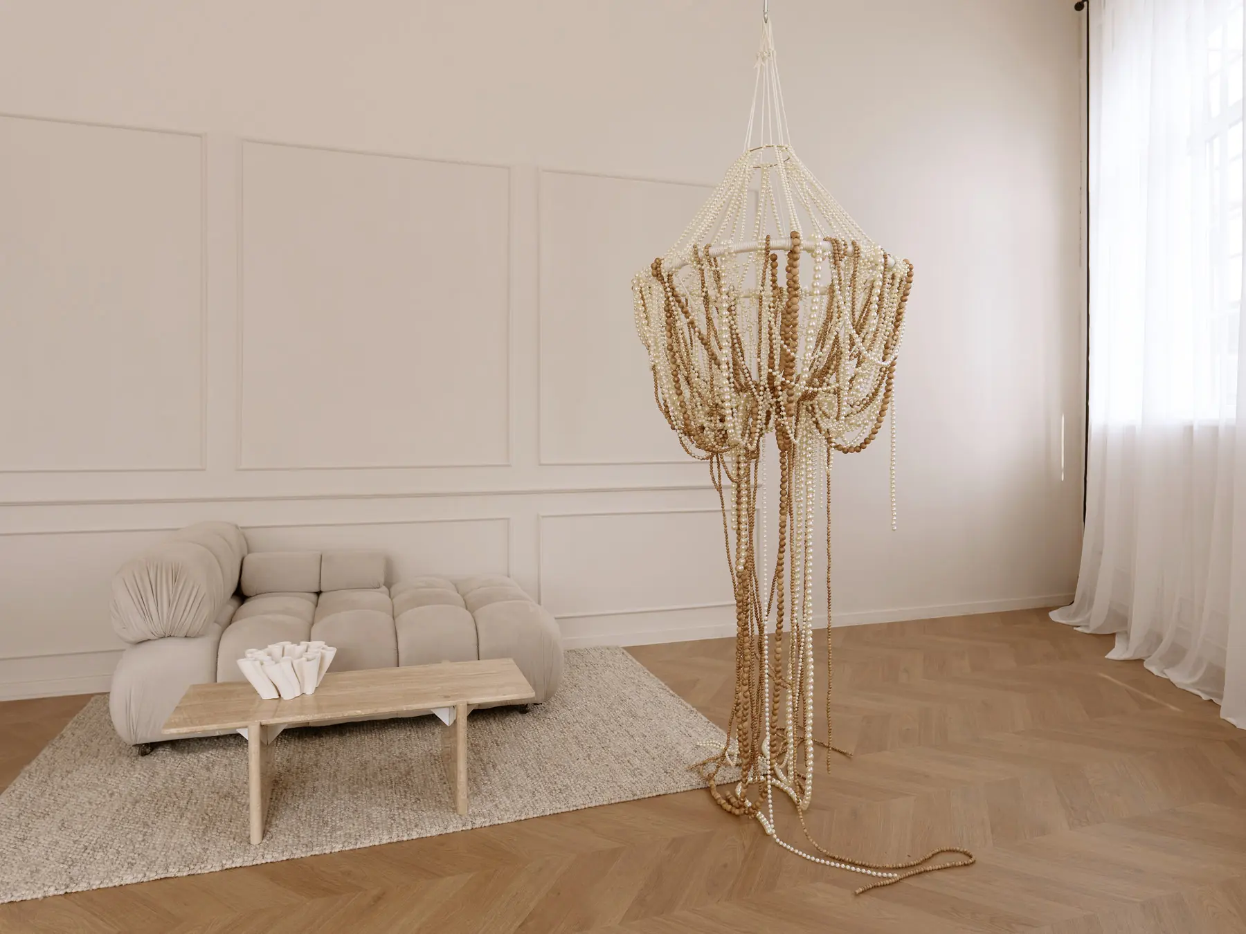 Home Chic zāle: pērļu lustra pilnā augumā, moduļu dīvāns un koka soliņš uz vilnas paklāja